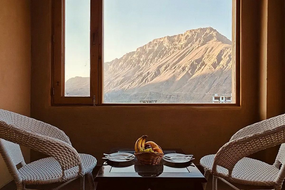 Two chairs at a window, a mountain peak beyond